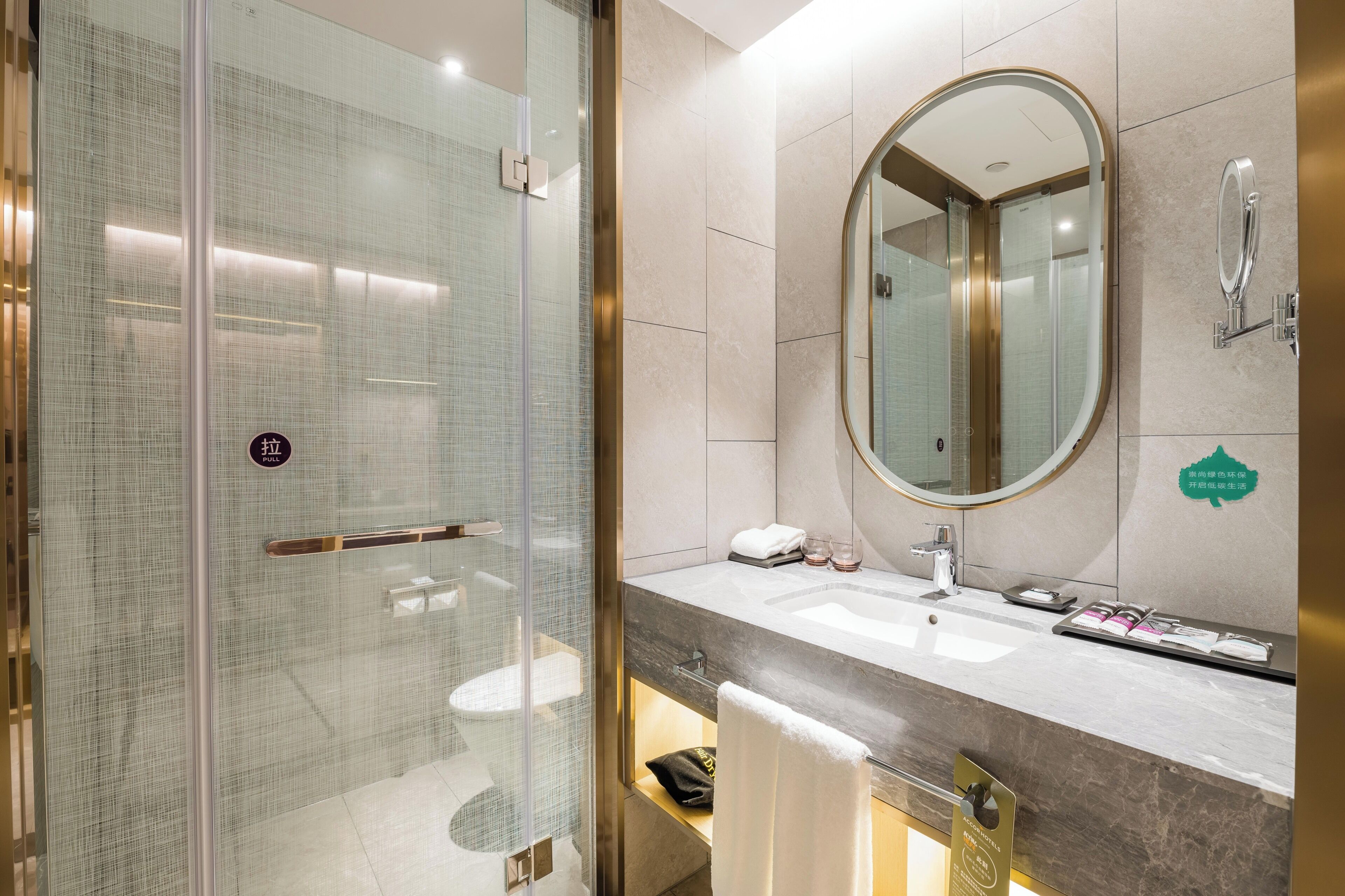 A modern bathroom with a glass-enclosed shower, a vanity with a large mirror, and a sink.
