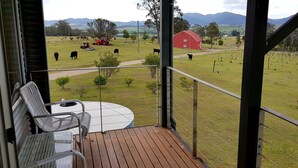 Un balcon avec vue sur une ferme, une grange rouge et un tracteur.
