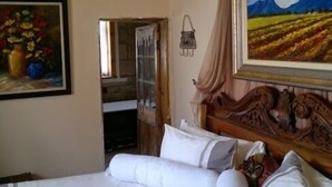 A bedroom with a large bed, a painting of a landscape, and a wooden headboard. - Rosenhof Country Lodge (Paul Roux)