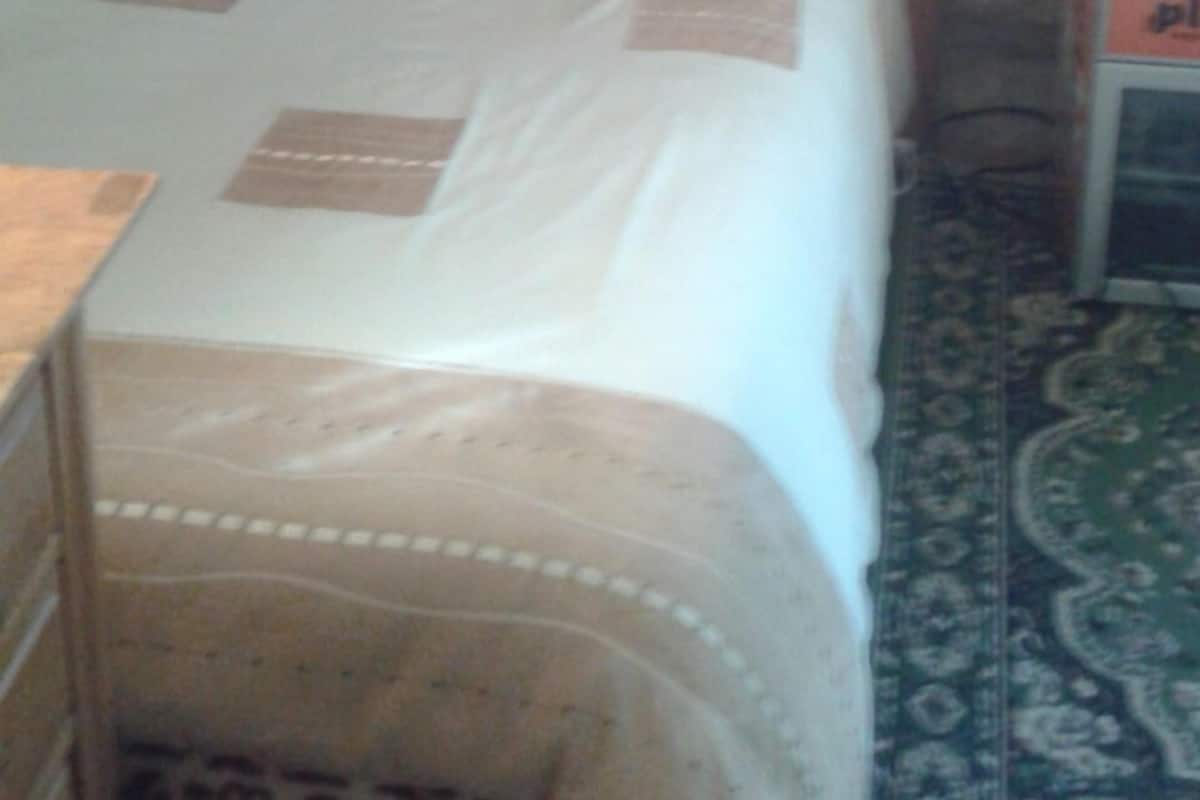 Ein kleiner, gemütlicher Raum mit einem hölzernen Bett, einem Nachttisch und zwei gerahmten Bildern an der Wand.
