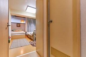 A hotel room with a bed, a desk, and a window with curtains. - Nishishinjuku Hana Apartment (Tokyo)