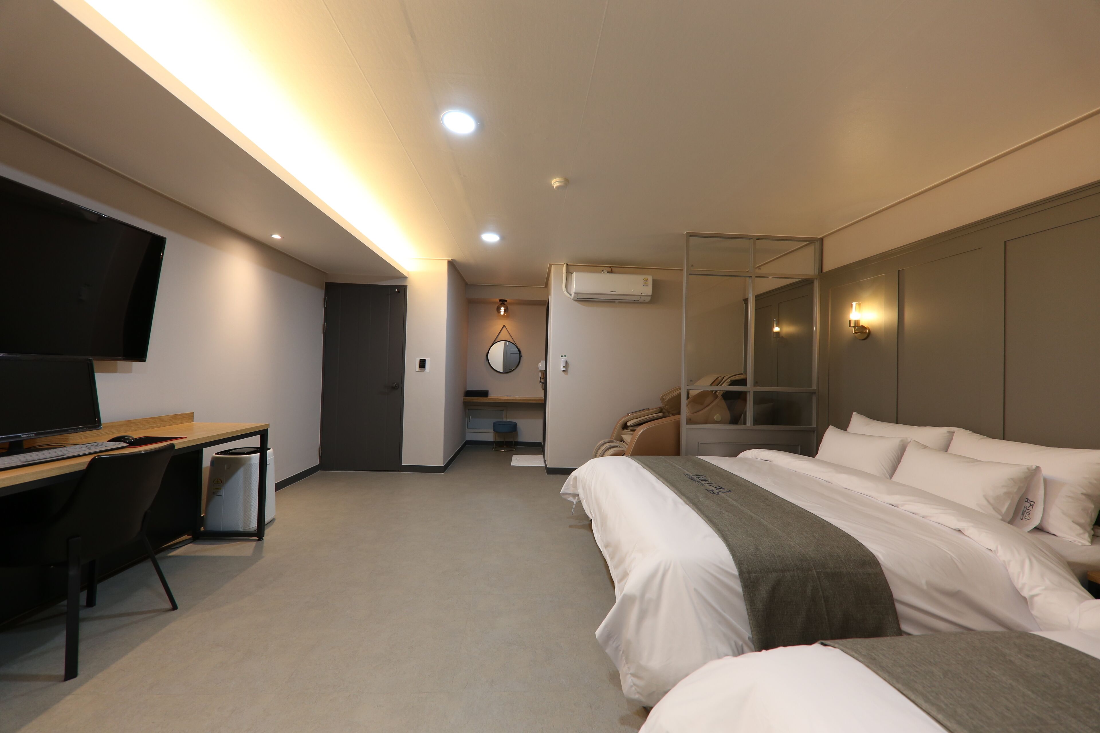 A hotel room with a bed, a desk, a TV, and a mirror.
