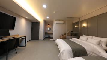 A hotel room with a bed, a desk, a TV, and a mirror.