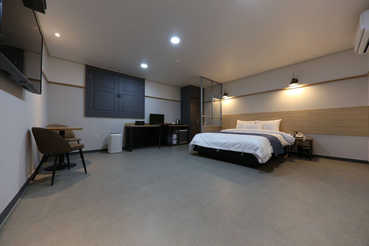 Una habitación de hotel moderna con cama, escritorio, silla y una mesita.
