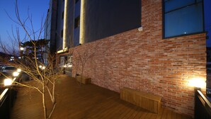 Una terraza de madera con un muro de ladrillo, un banco y un árbol.
