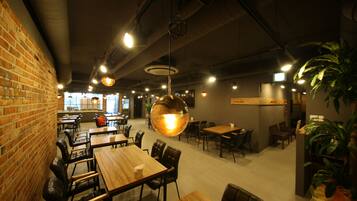 A spacious restaurant with brick walls, wooden tables, and hanging pendant lights.