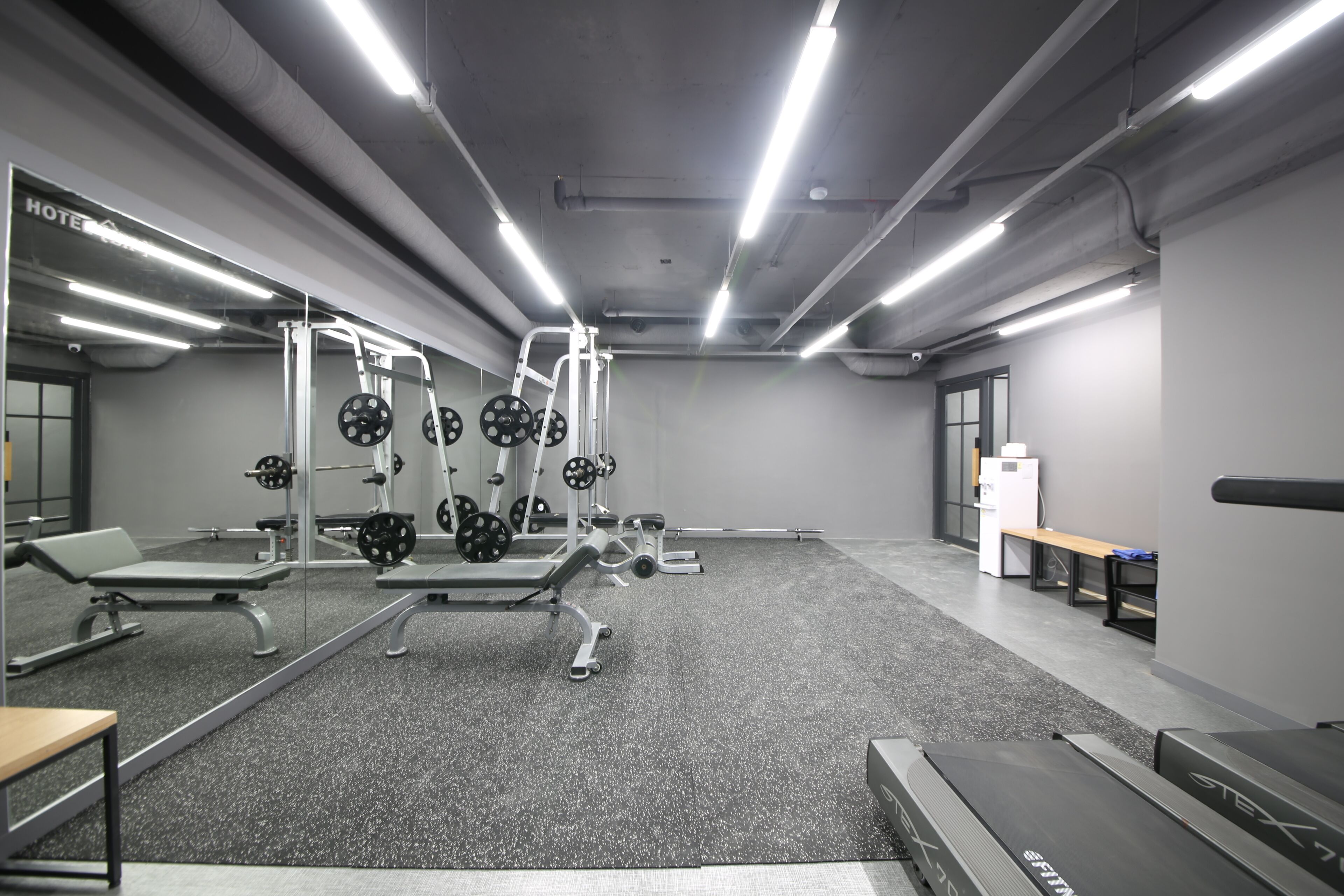 A gym with weightlifting equipment, benches, and treadmills.