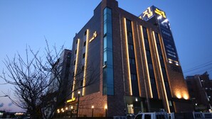 Un hotel con diseño arquitectónico moderno, que presenta detalles de iluminación vertical y señalización destacada que indica que está abierto.