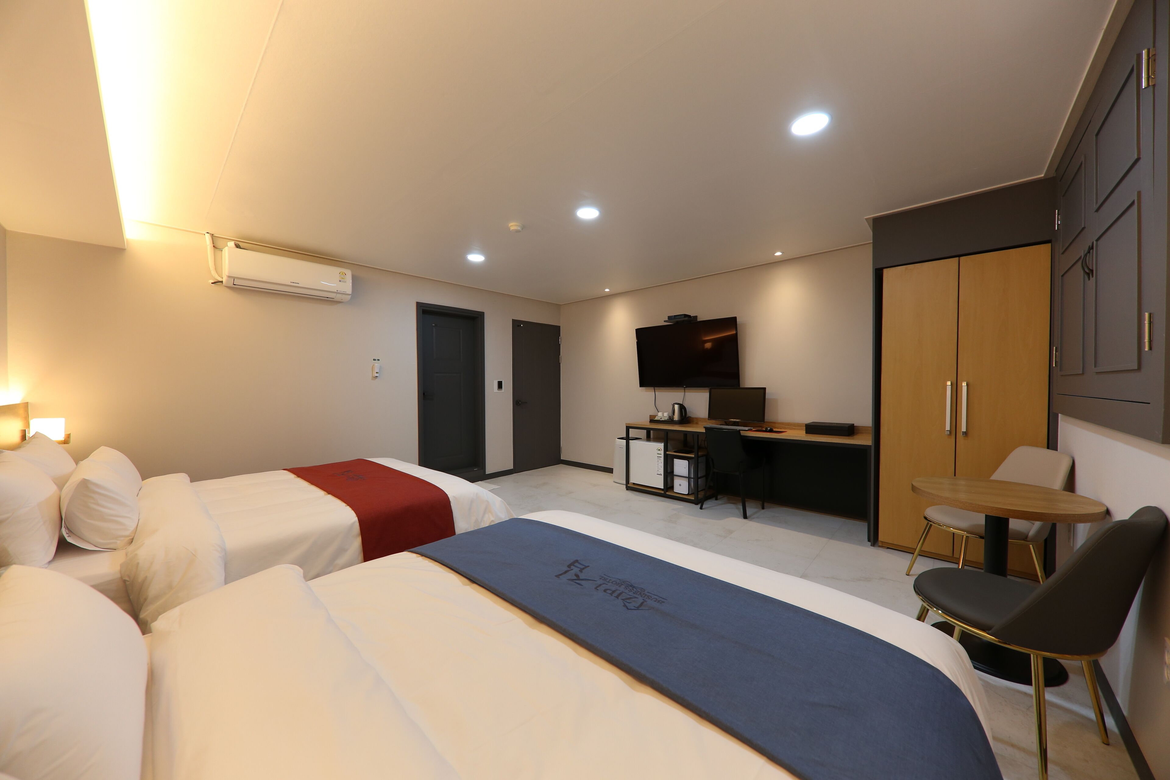Una habitación de hotel con dos camas, un escritorio, un televisor y un armario.