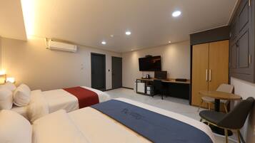 A hotel room with two beds, a desk, a TV, and a wardrobe.