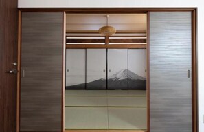 Une armoire à portes coulissantes dotée d’un cadre en bois et de portes en verre dépoli, avec un panneau central orné d’une image de montagne.