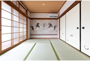 A traditional Japanese room with tatami flooring, sliding doors, and a mural on the wall.
