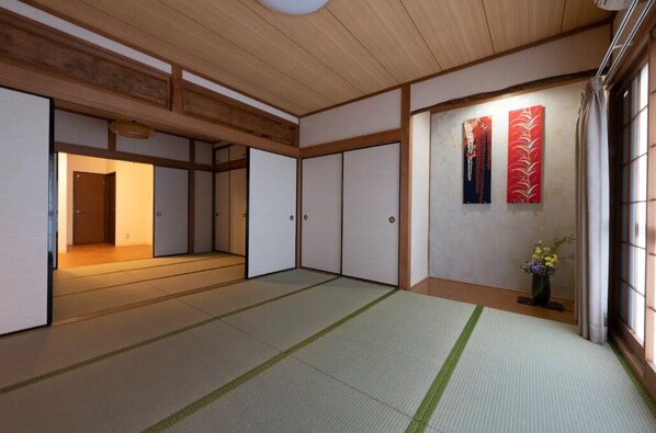 A traditional Japanese room with tatami flooring, sliding doors, and a wooden ceiling.