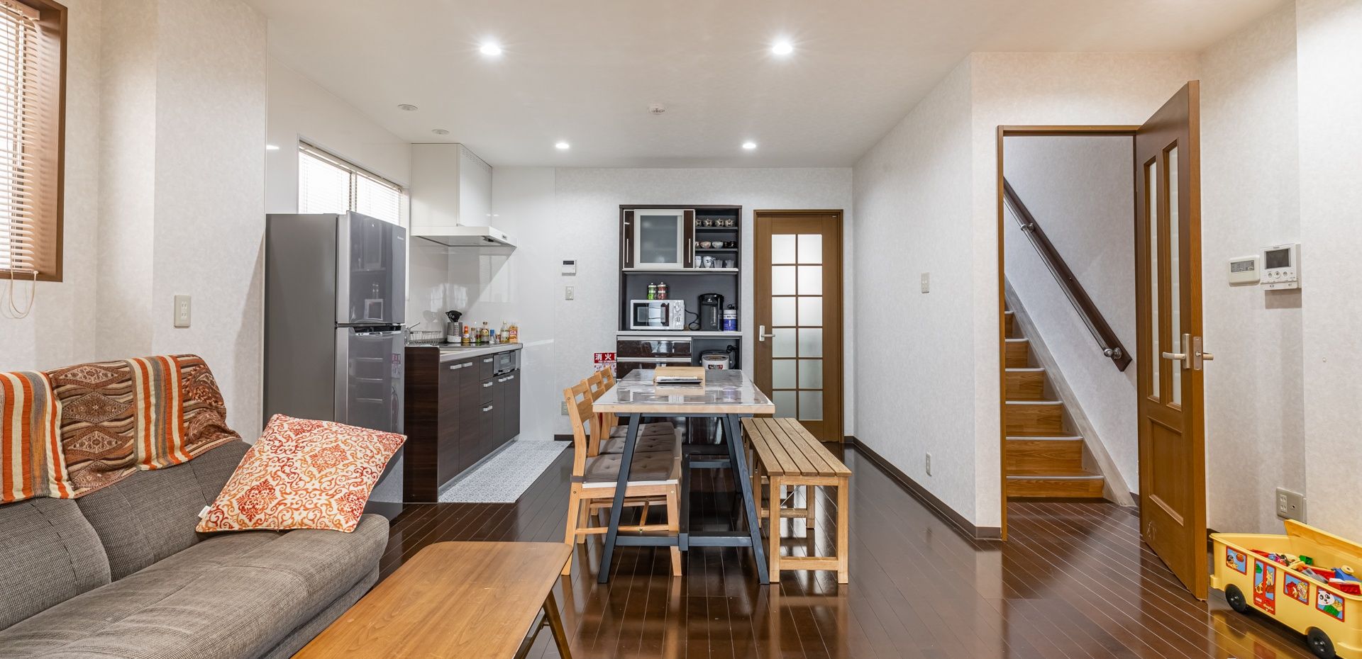A compact living space with a kitchenette, a dining area, and a staircase leading to an upper level.