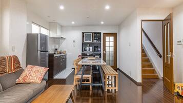 A compact living space with a kitchenette, a dining area, and a staircase leading to an upper level.