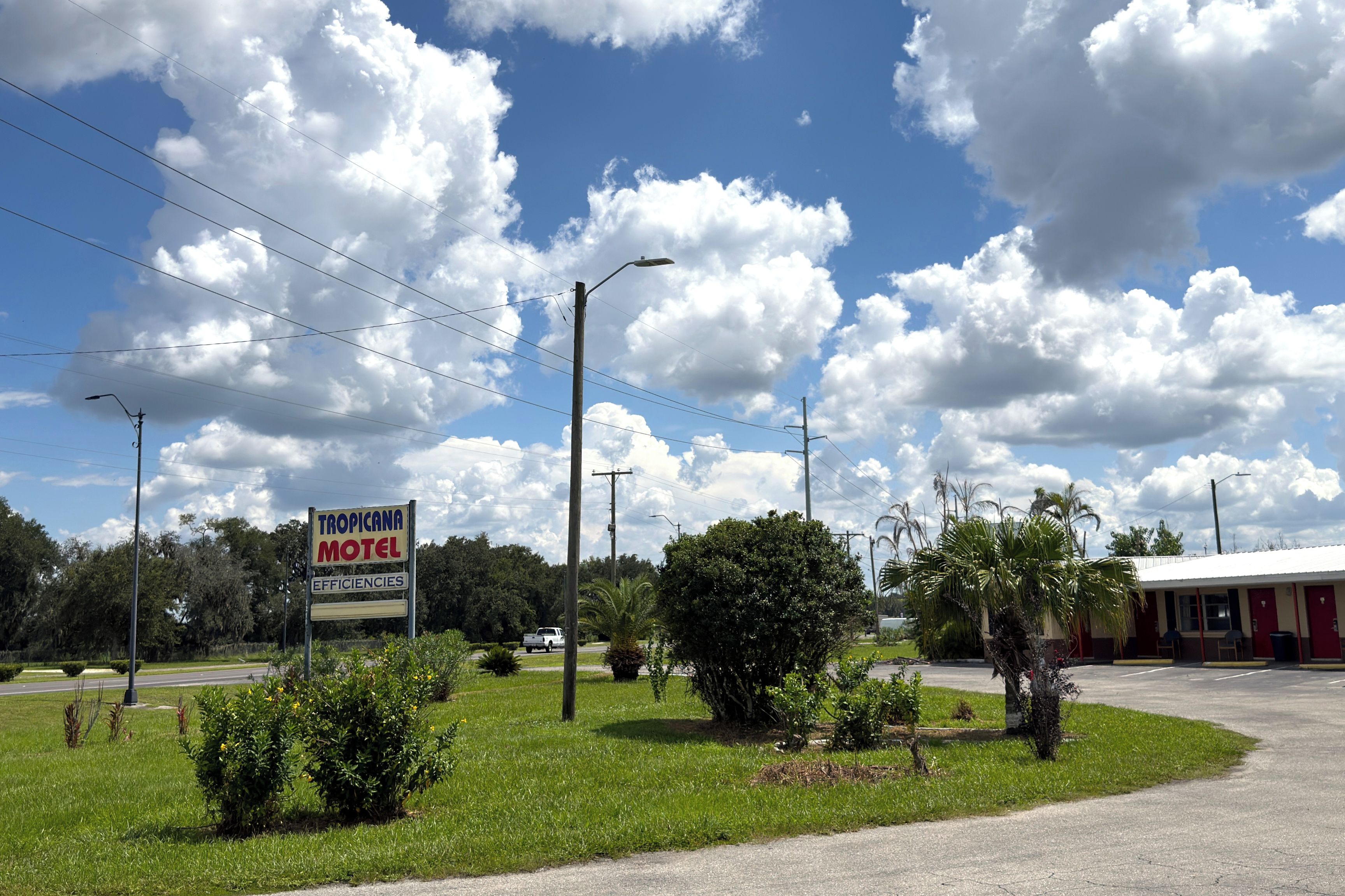 A motel with a signboard, surrounded by greenery and a clear sky.