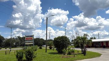 A motel with a signboard, surrounded by greenery and a clear sky.