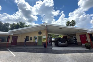 Un bâtiment doté d’un espace de stationnement couvert, d’un panneau d’affichage, d’un distributeur automatique de boissons Pepsi et d’un service de lavage automobile.