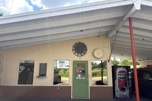 A building with a green door labeled 'OFFICE,' a clock, and a Pepsi vending machine. - Tropicana Motel Wauchula FL (Wauchula)