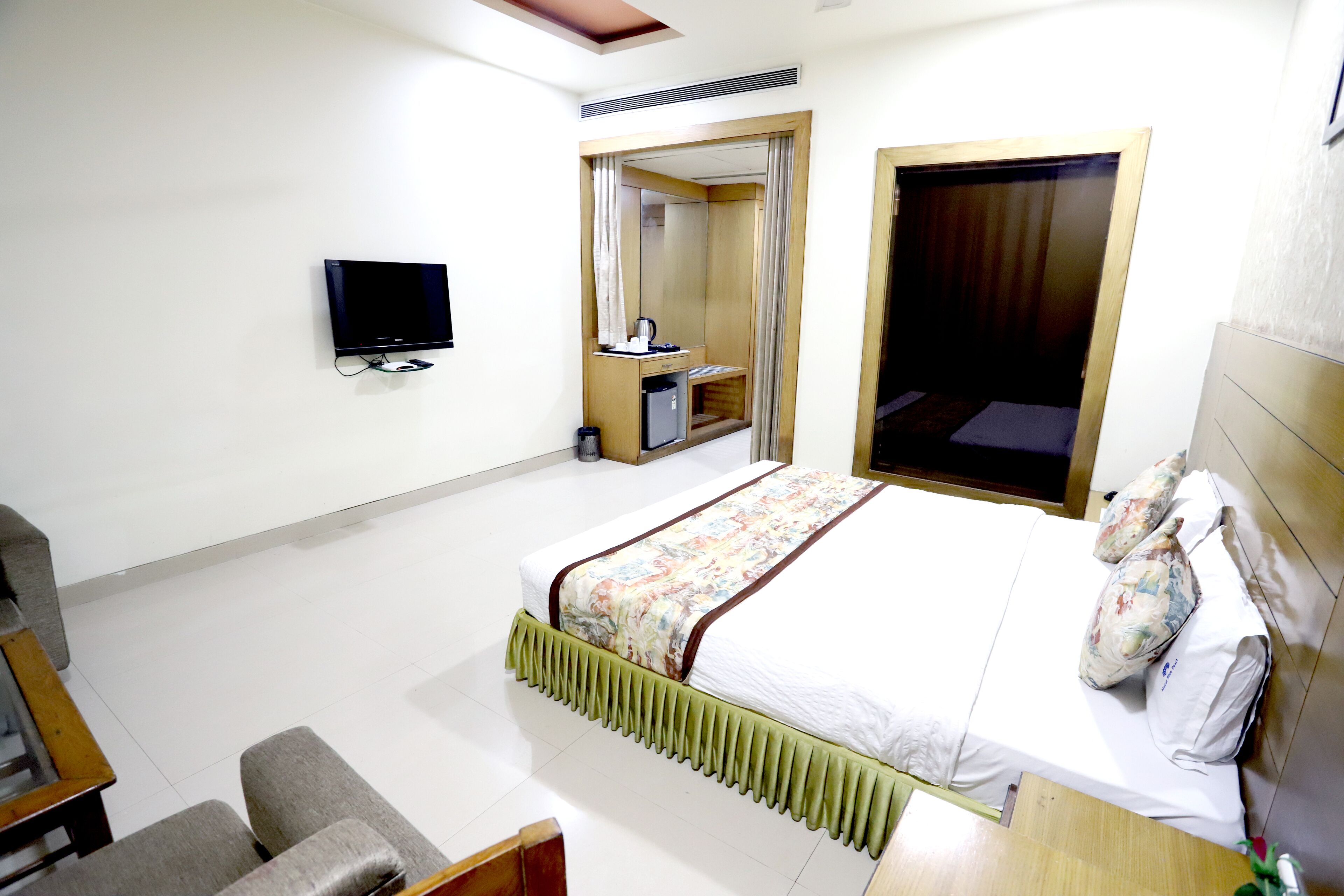 A hotel room with a bed, a TV, a desk, and a chair.