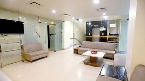 A modern living room with a sofa, a coffee table, and a flat-screen TV mounted on the wall. - HOTEL BLUE PEARL (Bhopal)