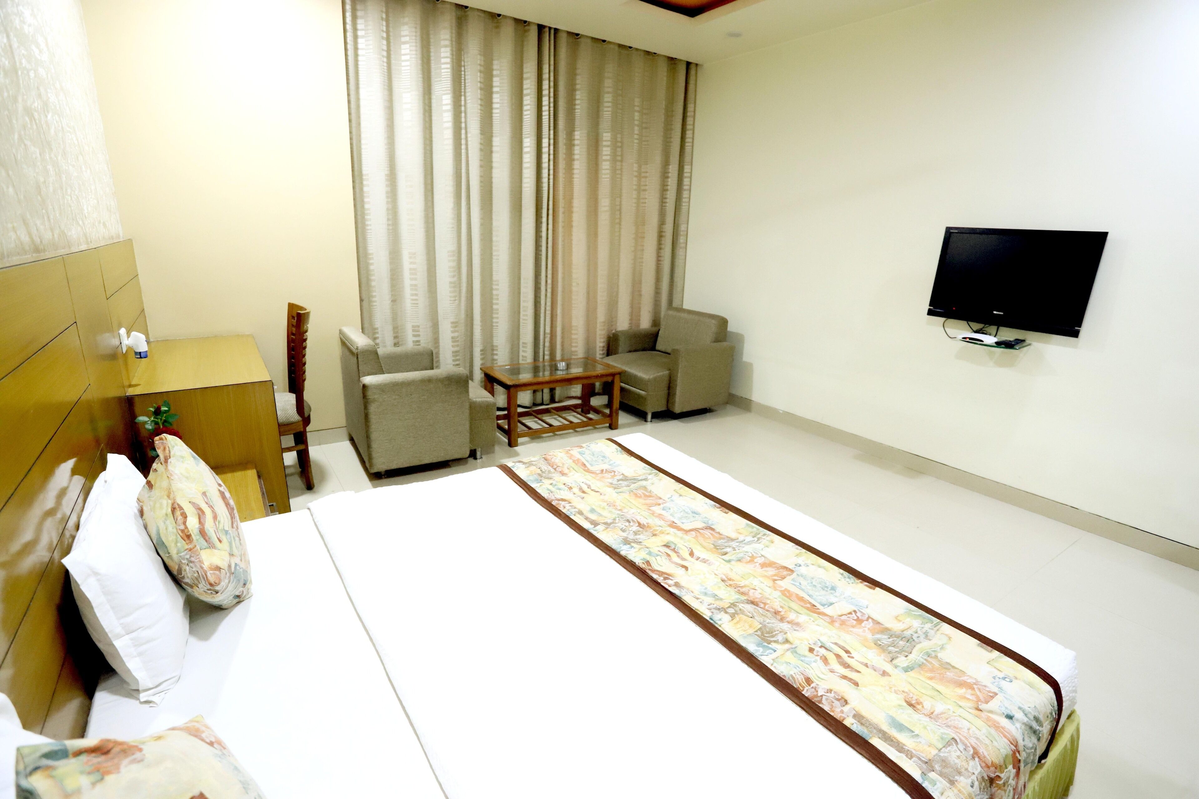 Ein Hotelzimmer mit einem Bett, einem an der Wand befestigten Fernseher, einem kleinen Tisch und zwei Stühlen.