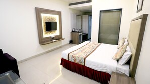 A modern hotel room with a large bed, a TV mounted on the wall, a desk with a chair, and a wardrobe. - HOTEL BLUE PEARL (Bhopal)