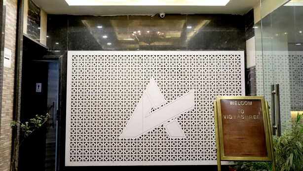 A reception area with a chandelier, a decorative wall, and a welcome sign. - HOTEL BLUE PEARL (Bhopal)