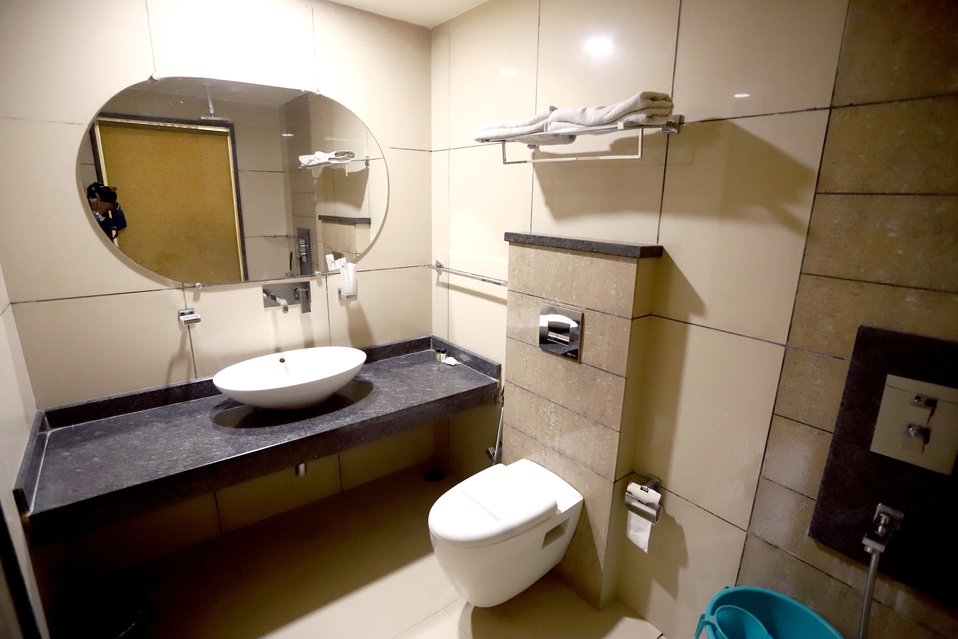 Een moderne badkamer met een ronde spiegel, een wit wastafel en een toilet.