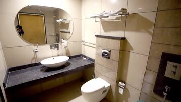 A modern bathroom with a round mirror, a white sink, and a toilet.