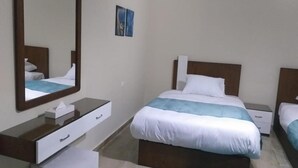Habitación de hotel con una cama grande, una mesita de noche, un espejo y una pequeña mesita de noche con una lámpara.
