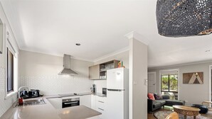 Una cocina moderna con armarios blancos, una campana extractora de acero inoxidable y un horno empotrado.