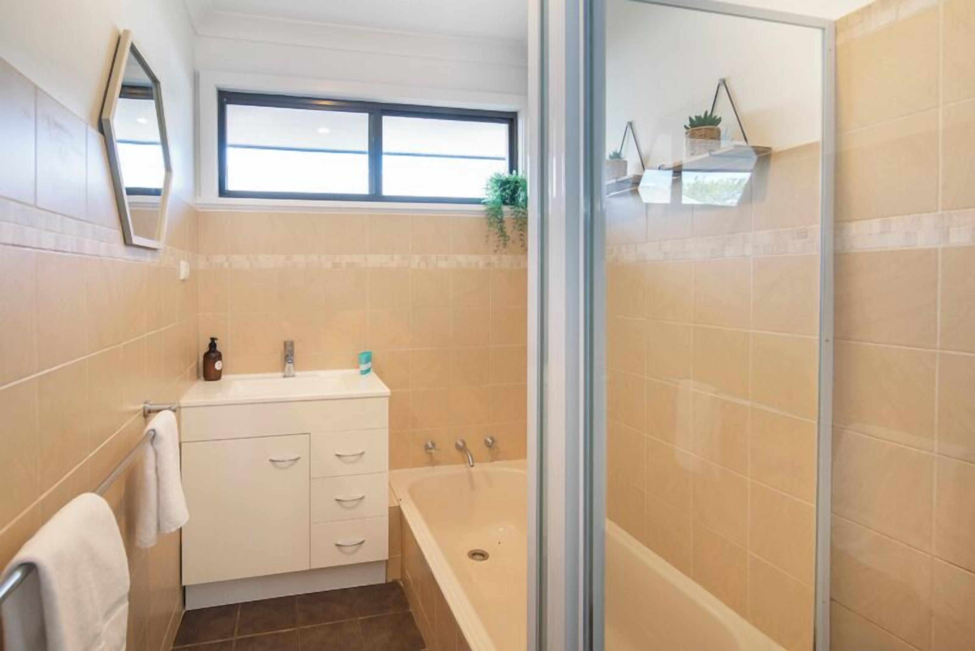 Un baño con una bañera, un lavabo y un ventanal.