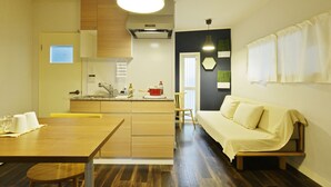 A compact living space with a kitchen, dining area, and a sofa. - Konpeito House (Osaka)