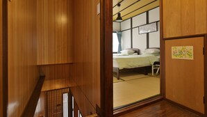 A traditional Japanese room with tatami flooring, a low wooden bed, and shoji screens. - Konpeito House (Osaka)