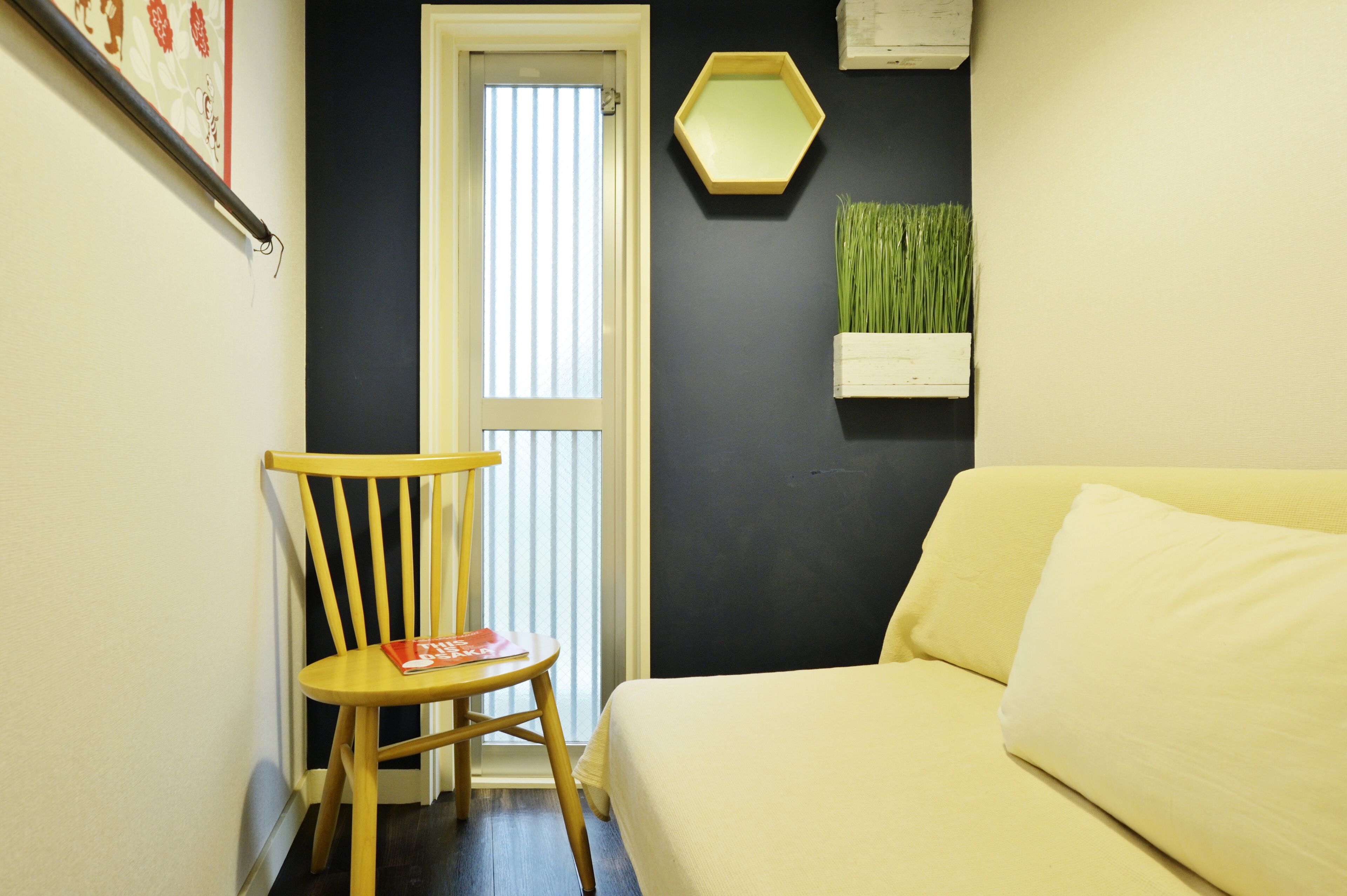 A room with a bed, a chair, a door, and a wall-mounted mirror.