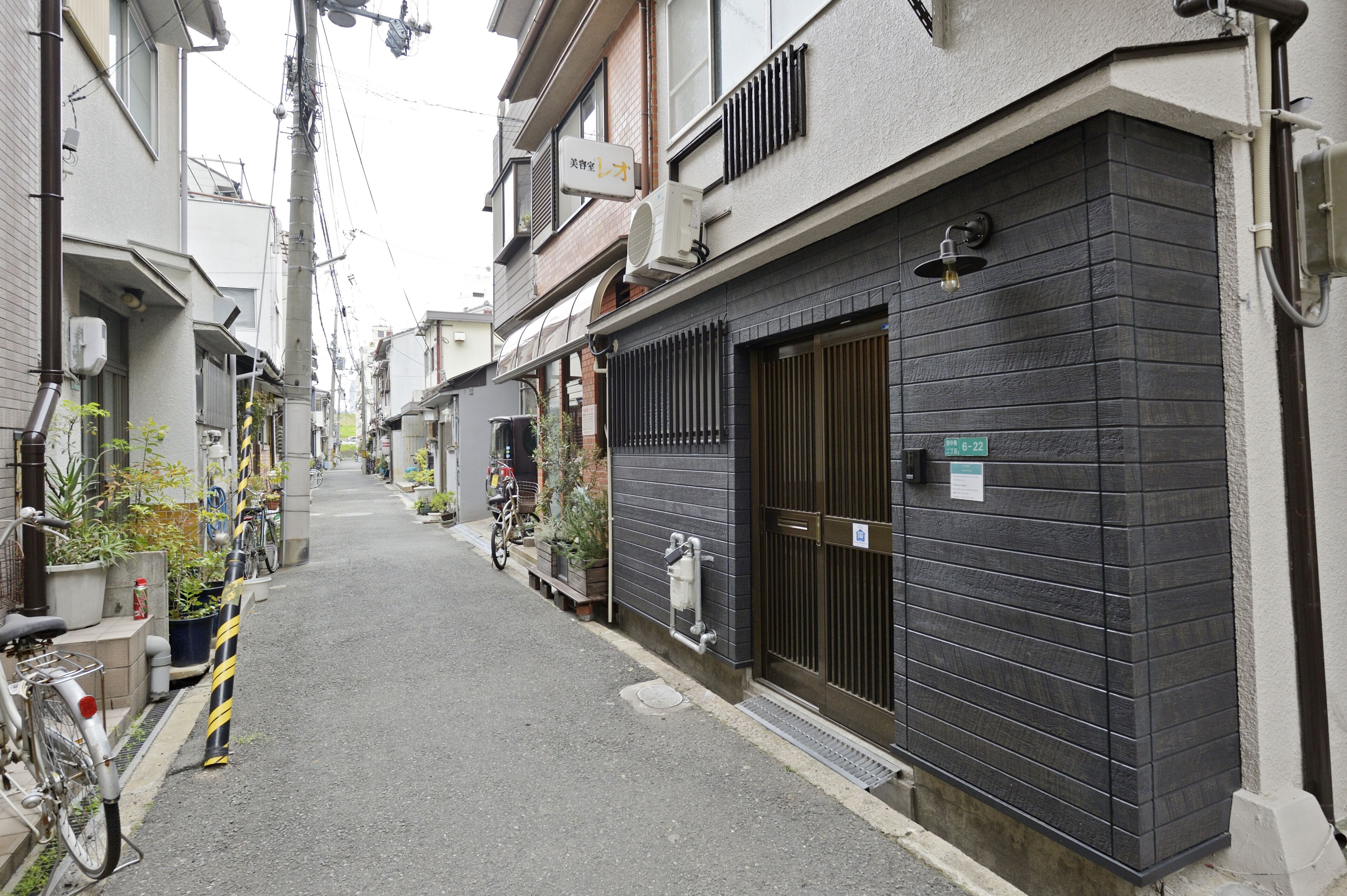 A narrow residential street with houses on both sides, a gated entrance, and a bicycle parked on the sidewalk.