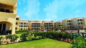 A hotel with multiple floors, outdoor swimming pool, and well-maintained garden area. - Marseilia Beach 3 (Al-Hammam)