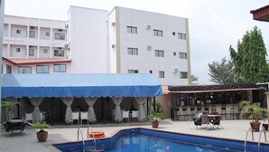 A swimming pool with a blue canopy, outdoor seating, and a bar area. - Channel View Hotel (Calabar)