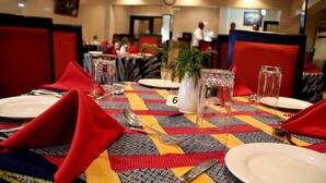 A dining area with tables set for four, each with a numbered placemat, red napkins, and clear glassware. - Channel View Hotel (Calabar)