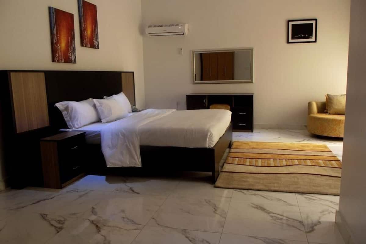 A bedroom with a bed, nightstands, a dresser, a mirror, a chair, and a rug.