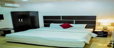 A neatly arranged bedroom with a large bed, a bedside table, a lamp, and a wardrobe.