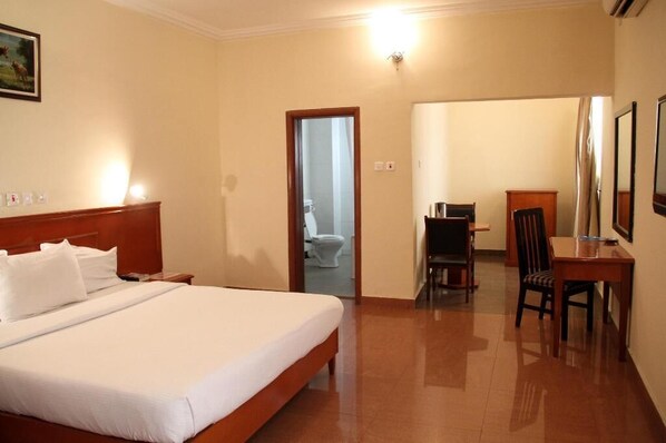 A hotel room with a bed, a desk, a chair, and a television.