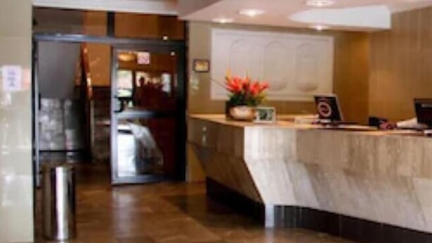 A reception area with a marble counter, a trash bin, and a door leading to another room. - Channel View Hotel (Calabar)