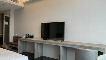 Een hotelkamer met een bed, een bureau met een flatscreen televisie, een stoel en een kleine tafel met een koffiezetapparaat.