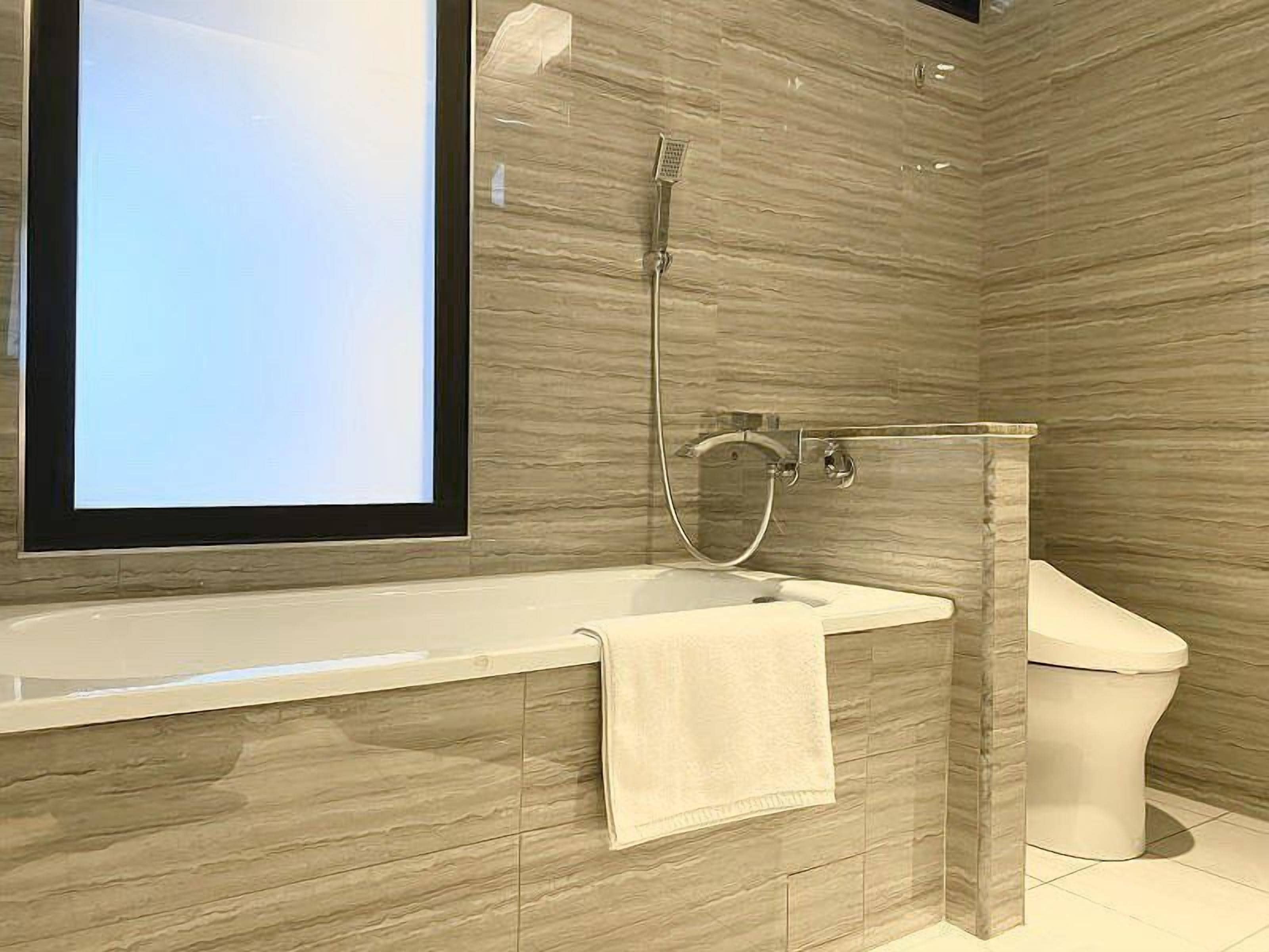 A modern bathroom with a large bathtub, a shower, and a toilet.