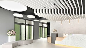 A modern reception area with a marble reception desk, large windows, and a curved seating area. - Champ de Roses Hotel (Hualien City)