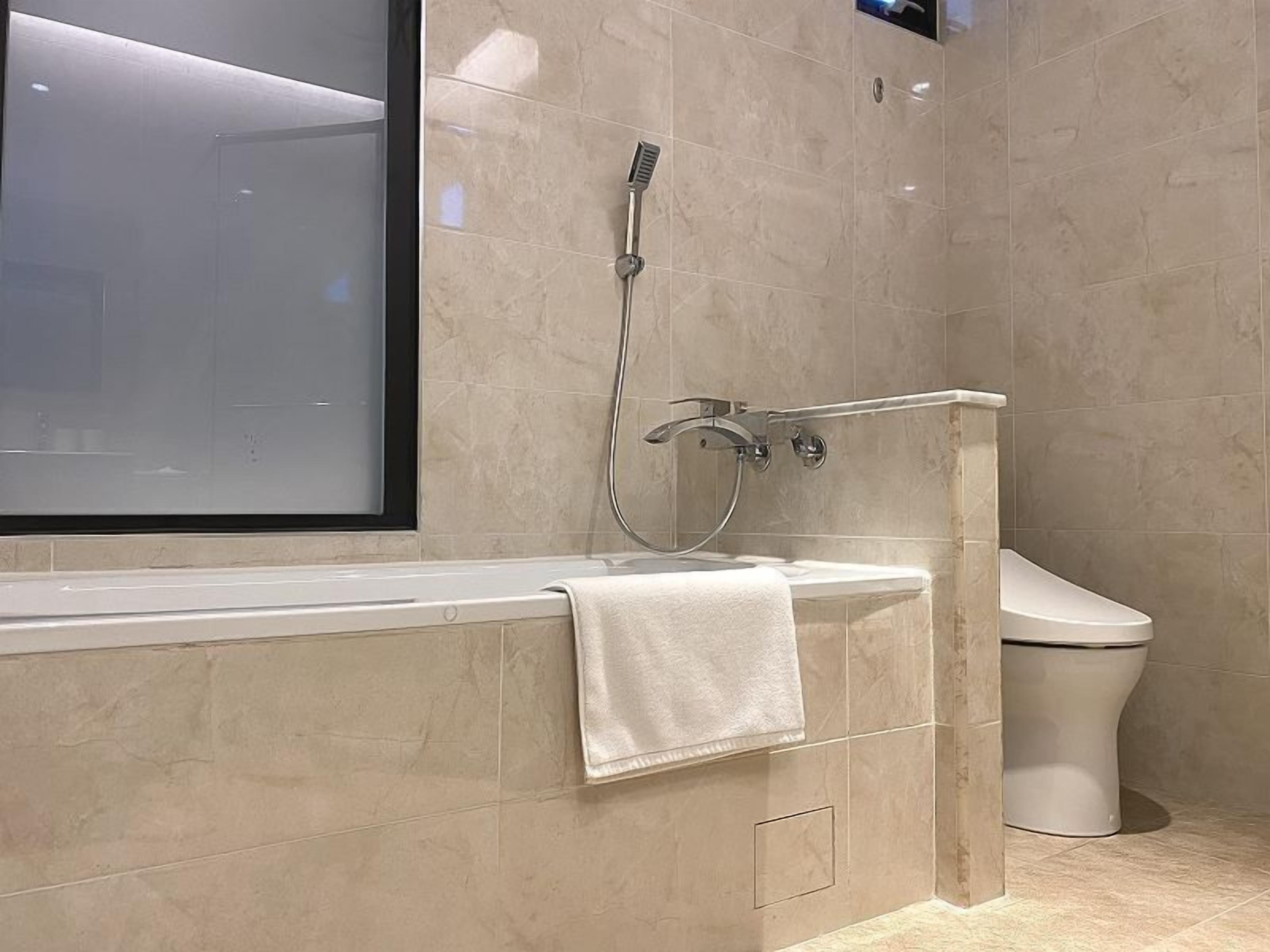 A modern bathroom with a bathtub, a shower, and a toilet.