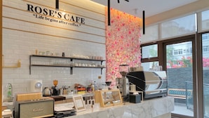 A cafe interior with a marble counter, coffee machines, and a wall decorated with flowers. - Champ de Roses Hotel (Hualien City)