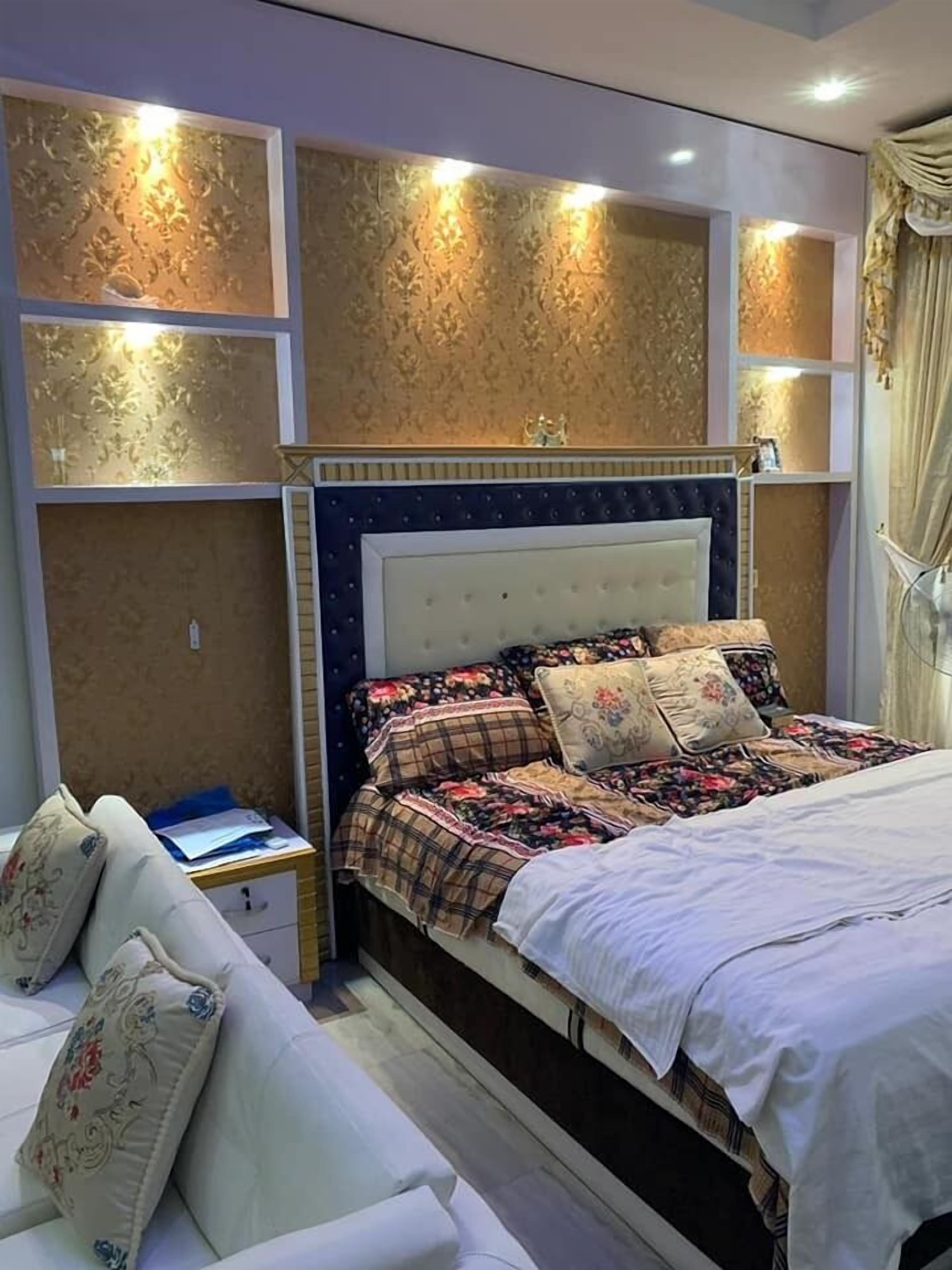Ein Schlafzimmer mit einem großen Bett, einem Nachttisch, einer Couch und dekorativen Wandverkleidungen.